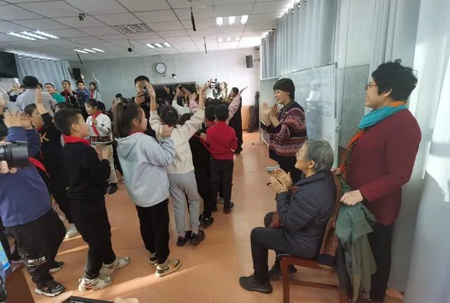 Deng Xiaolan watches the children perform; Xinhua profile photograph.
