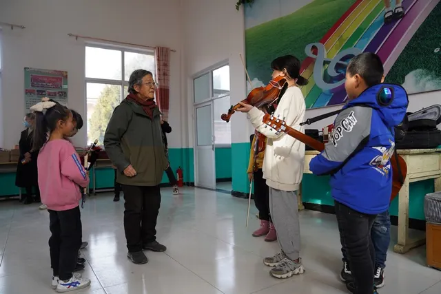 Teaching music to children in Malan village; Xinhua archive photograph.