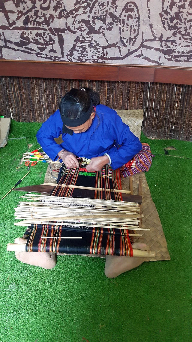 Li textile weaving in Hainan, using a handloom tensioned with the feet; not a verified Haikou workshop booking.