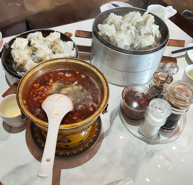A photograph of Inner Mongolian shaomai served with dubaorou; distinguish the dumpling steamer from the other dish.