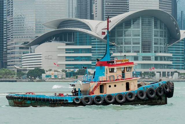 A towboat on Victoria Harbour, with the Hong Kong Convention and Exhibition Centre behind it.