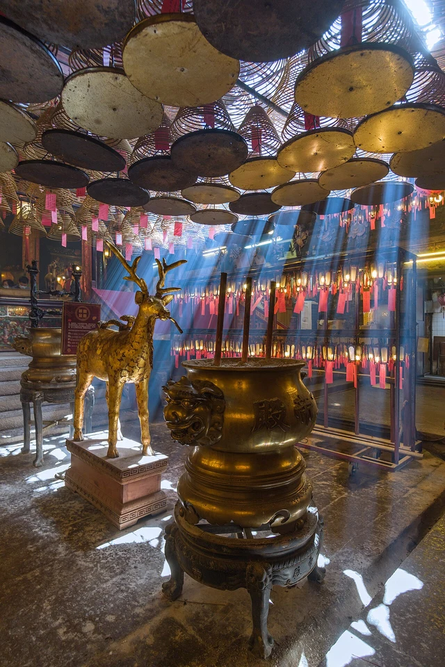 Light and incense smoke inside Man Mo Temple on Hollywood Road, Sheung Wan.