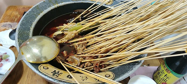 Bobo chicken skewers resting in a large bowl of sauce in Chengdu.