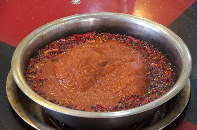 A red Sichuan-style hotpot soup base from Chongqing in a metal pot.