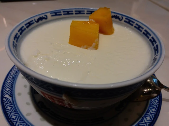 A bowl of double-skin milk dessert topped with mango.
