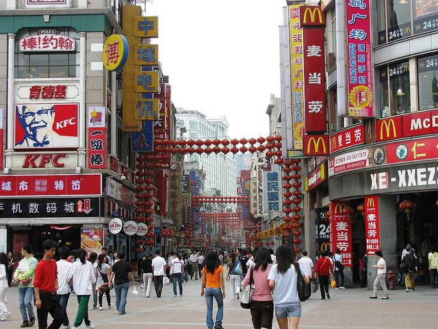 Shangxiajiu pedestrian street in Guangzhou with shoppers and commercial signs.