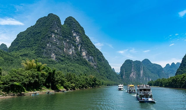 Cruise boats travelling between green limestone peaks on the Li River in Guangxi.