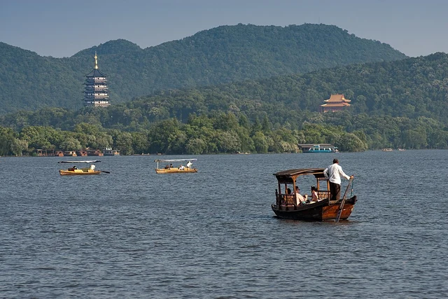 Rowboats on Hangzhou's West Lake with Leifeng Pagoda in the wooded distance.