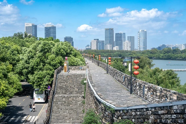 The ramparts and walkway of Nanjing City Wall, with a lake and skyline beyond.