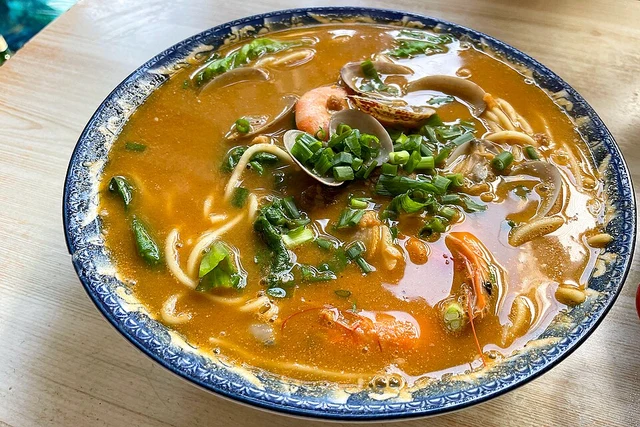 Seafood shacha noodles in an orange broth in Xiamen in January 2023.