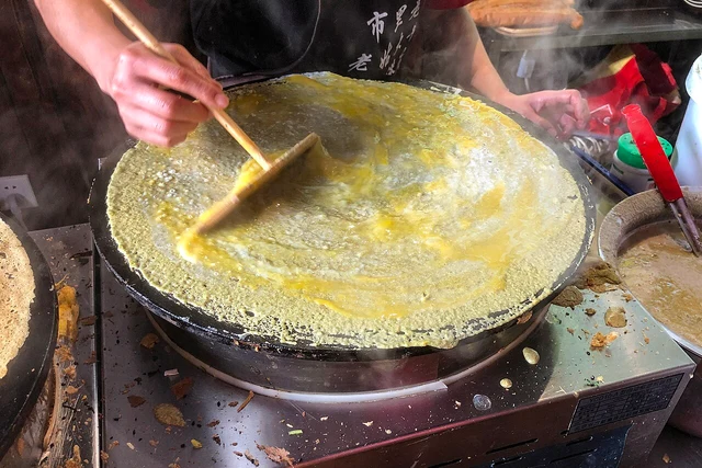 Spreading egg during jianbing preparation in Binhai, Tianjin, in October 2019.