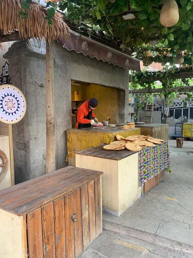 A naan baker and the oven-side workspace at an Erdaoqiao bakery in Urumqi.