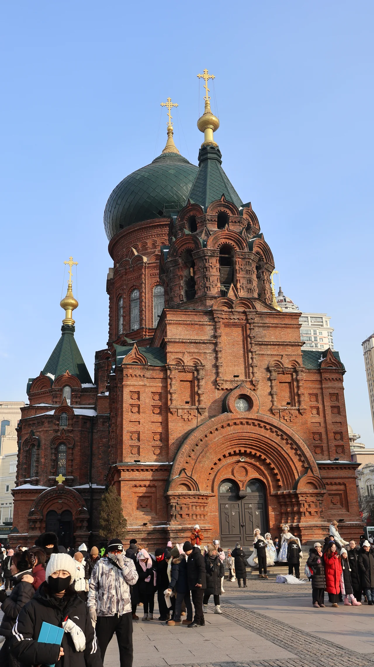 The green domes and brick facade of Saint Sophia Cathedral on a winter day in Harbin.