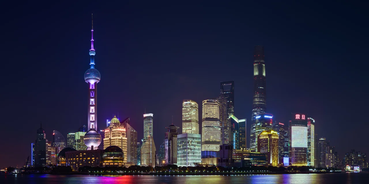 The illuminated Pudong skyline viewed across the Huangpu River at blue hour.