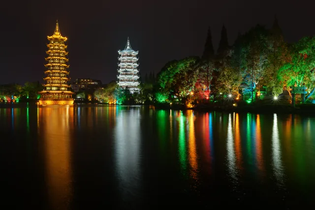 The illuminated Sun and Moon Pagodas reflected in Shanhu Lake in Guilin.