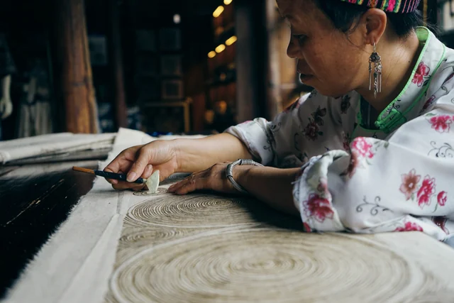 An artisan works on the intricate wax-resist pattern of a Miao batik textile in Guizhou.