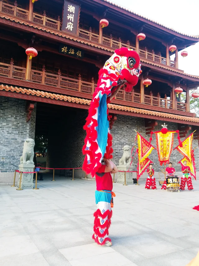 A bright lion costume and performers on a street in Chaozhou, Guangdong.