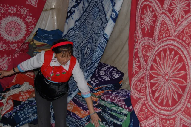 An artisan surrounded by indigo-and-red patterned textiles at a dye workshop in Dali, Yunnan.