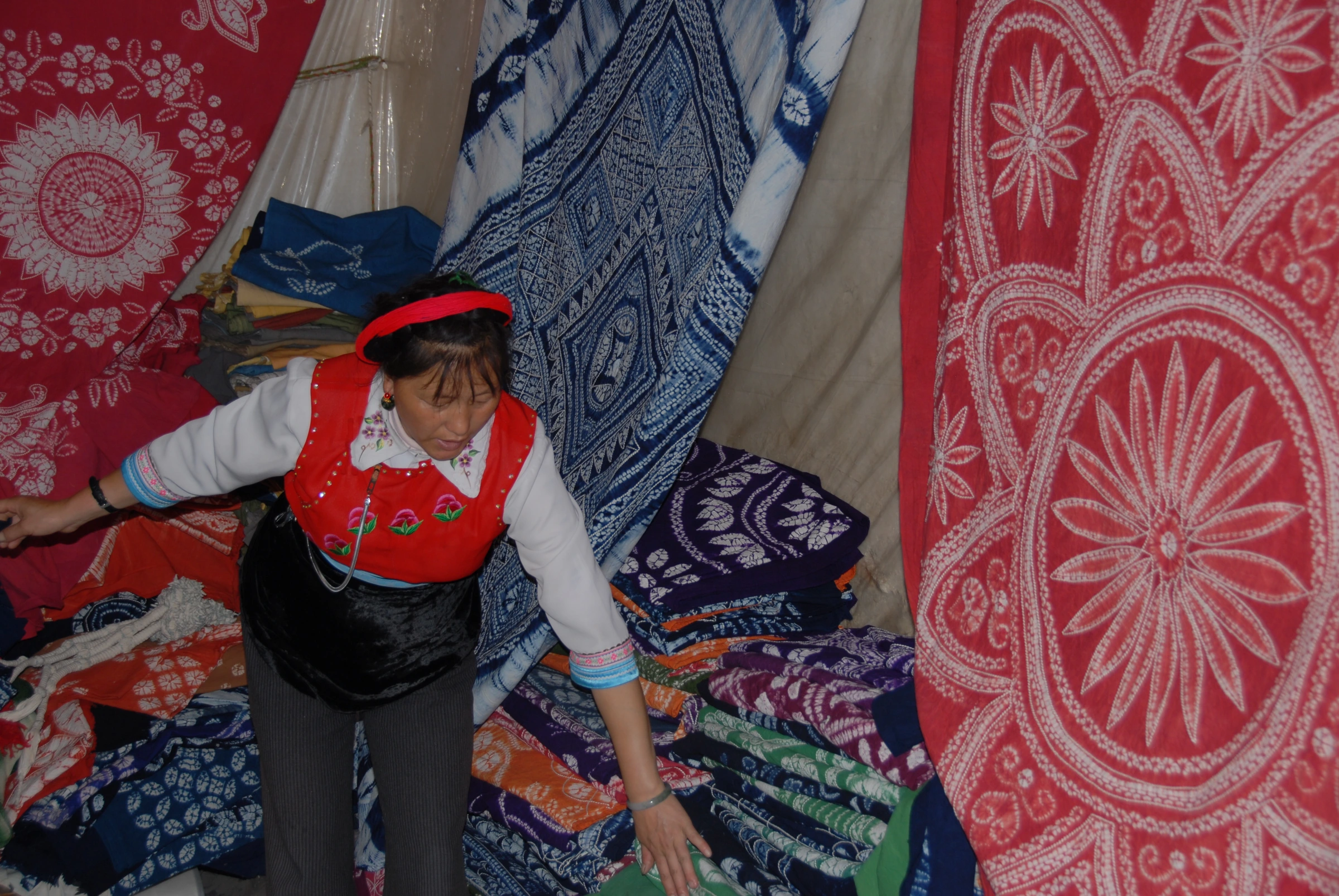 An artisan surrounded by indigo-and-red patterned textiles at a dye workshop in Dali, Yunnan.