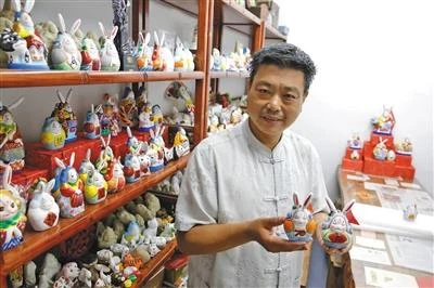 Beijing rabbit-figure artisan Zhang Zhongqiang holding painted Tu'er Ye clay figures in his workshop in September 2019.