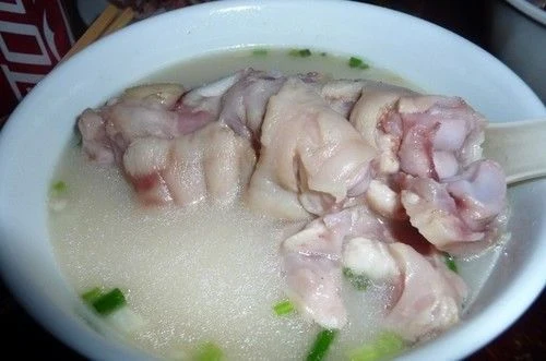 Chengdu-style pork trotters in a bowl of pale broth with scallions.