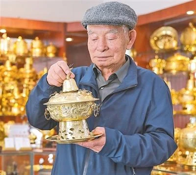 Datong copperware artisan Li Anmin examining a decorated copper hotpot.