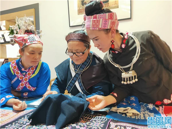 Wang Qiping demonstrates Huaxi Miao embroidery to two women at Xiuhuaxi Living Museum, published in June 2021.