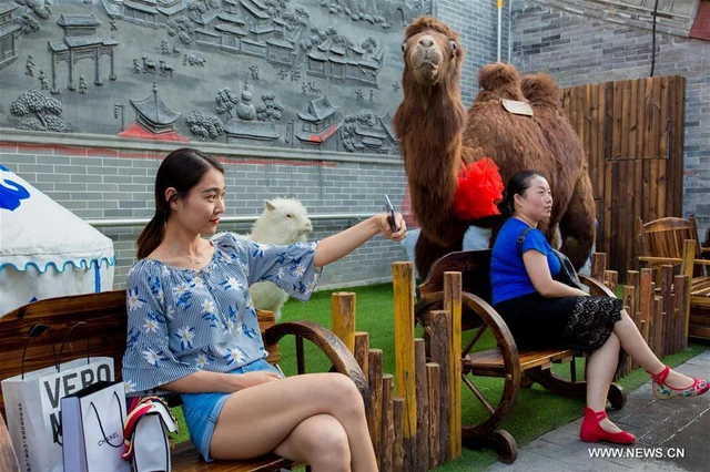 A visitor takes a selfie in Tongshun Lane food street, Hohhot, on 20 June 2017, photographed by Xinhua’s Ding Genhou.