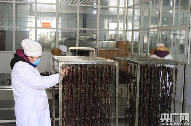 A worker tending racks of yak jerky in a production workshop in Riwoqe, Tibet.