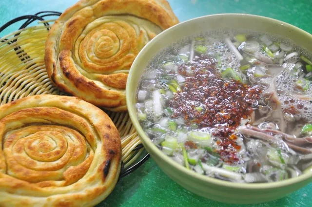 A bowl of Luoyang beef soup beside baked flatbreads, in Laocheng’s official December 2024 food report.