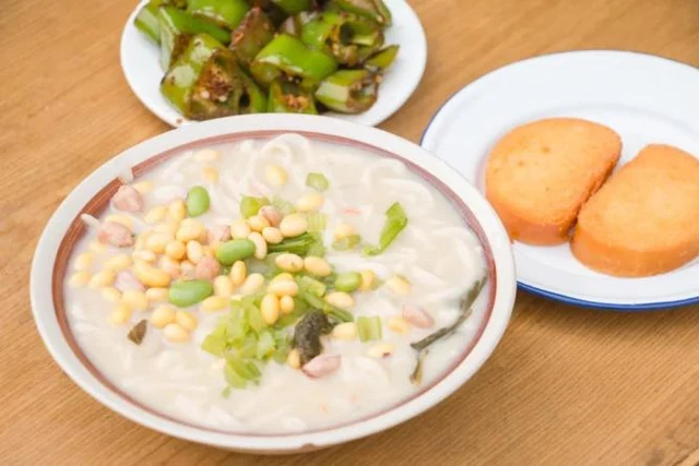 A Luoyang jiangmiantiao meal with beans and vegetables, in the local government’s 2023 food feature; accompanying dishes remain in the full frame.