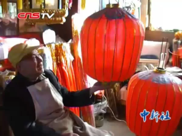 Luoyang palace-lantern maker Wang Fuxin with red lanterns, on China News Service’s original January 2011 documentary cover image; original CNS TV marks retained.
