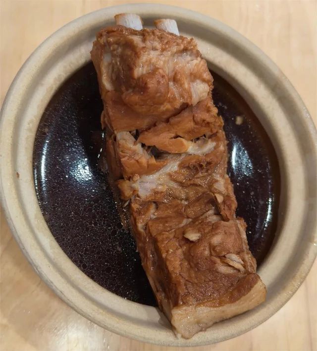 Pork ribs in a dark broth at Qingdao’s Wanhechun, photographed in Jiangsu News Radio’s June 2024 on-site report; rice is not pictured.
