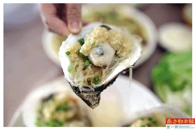 A garlic-topped roasted oyster on its half-shell in a report about Shenzhen Shajing oyster cuisine.