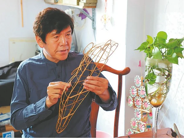 Wei Guoqiu works on a bamboo kite frame, in a China Daily photograph published with Flights of Kites on 30 April 2024.
