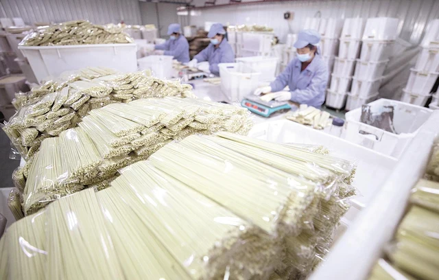 Workers packaging sealed hot-dry-noodle bundles at a Hubei food-production workshop in March 2021.