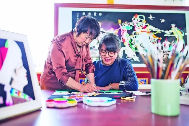 Qiao Yingju and Liu Qingwen work together on Huangzhong appliqué, in their supplied photograph published in June 2024.