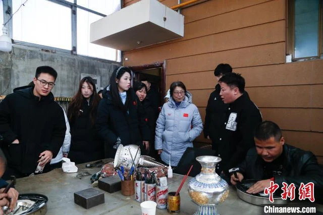 Visitors observe a metalworker at Huangzhong’s silver and copper craft base in March 2025, photographed by China News Service’s Ma Mingyan.