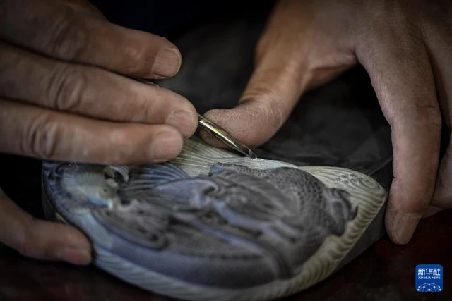 Yan Senlin carves wave patterns into a Helan inkstone on 8 March 2024; photograph by Feng Kaihua/Xinhua.