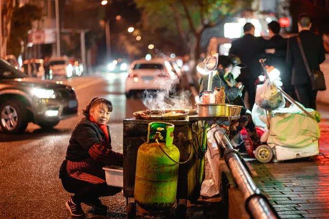 A cook prepares food at a small street-food stand in Chongqing.