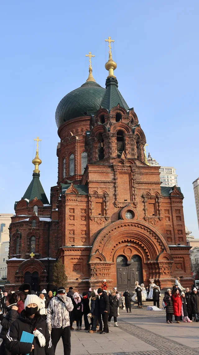 Saint Sophia Cathedral and visitors in winter coats on a clear January day in Harbin.