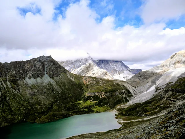 Clouds drift across rocky mountain peaks above Leshitso, also called Snake Lake, in Yading, Sichuan.